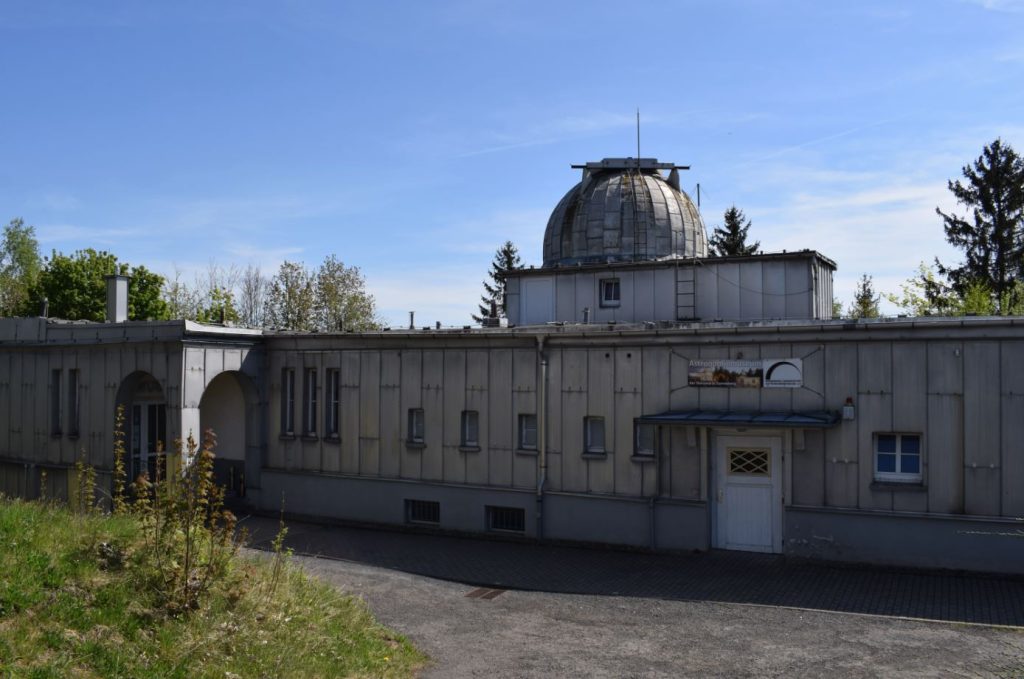 Kuppel und MUseum der Sternwarte in grauer Aluminiumverblendung und blauem Himmel im Hintergrund.