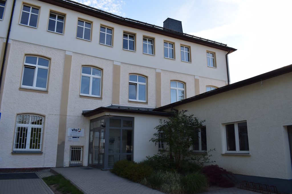 Dreistöckiges Gebäude der VHS mit Eingang im Zentrum des Bildes.
