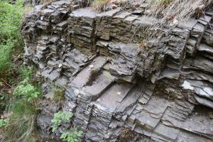Dunkelgraues Gestein mit mehreren Schichten.