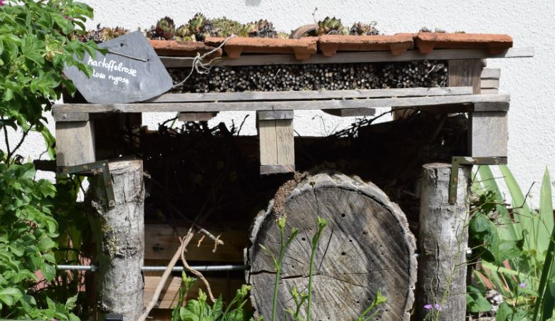 Insektenhotel aus verschiedenen Naturmaterialien auf einer Wiese.